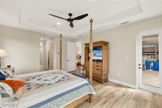 bedroom with visible vents, baseboards, access to outside, a tray ceiling, and light wood-style floors