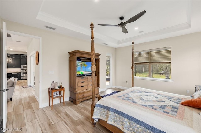 bedroom with light wood finished floors, baseboards, visible vents, a raised ceiling, and ornamental molding