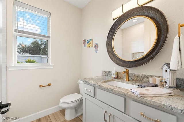 bathroom featuring a wealth of natural light, baseboards, vanity, and toilet