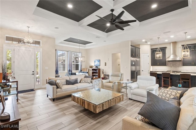 living area featuring recessed lighting, ceiling fan with notable chandelier, coffered ceiling, light wood-style floors, and crown molding