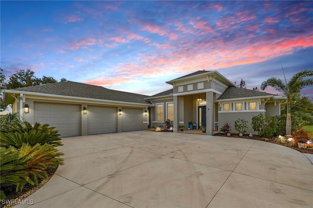 prairie-style home with a garage, concrete driveway, and stucco siding