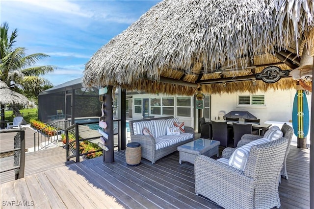 wooden terrace featuring glass enclosure, grilling area, and an outdoor hangout area