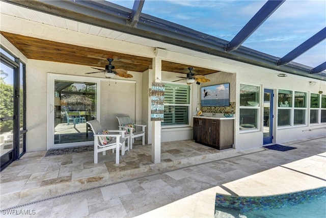 view of patio / terrace with ceiling fan, sink, and a lanai