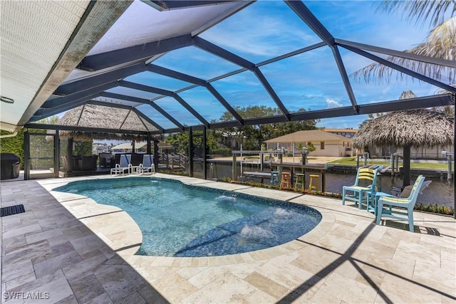 view of pool with glass enclosure, a patio area, and a water view