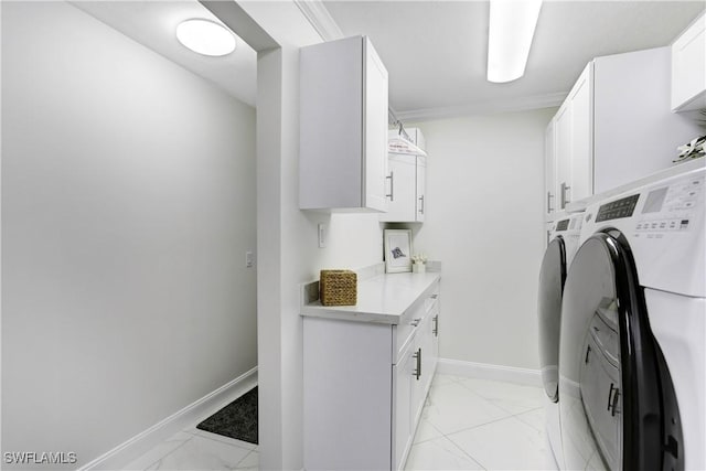 laundry area featuring washer and dryer, ornamental molding, and cabinets