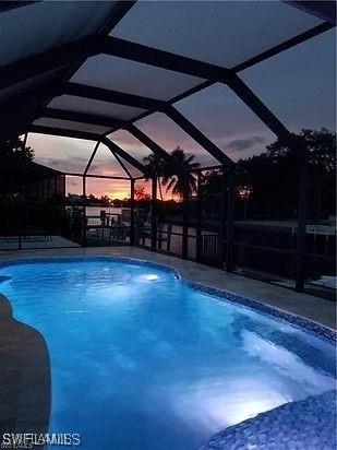 pool at dusk featuring a lanai