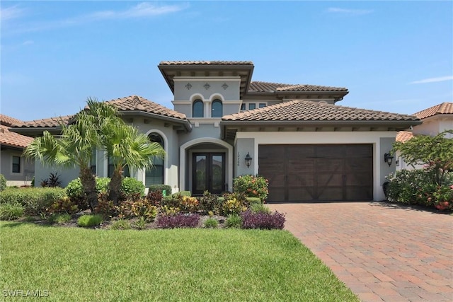 mediterranean / spanish house with a front yard, a garage, and french doors