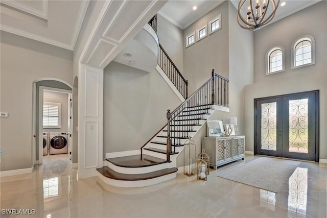 foyer with crown molding, a high ceiling, separate washer and dryer, french doors, and a chandelier