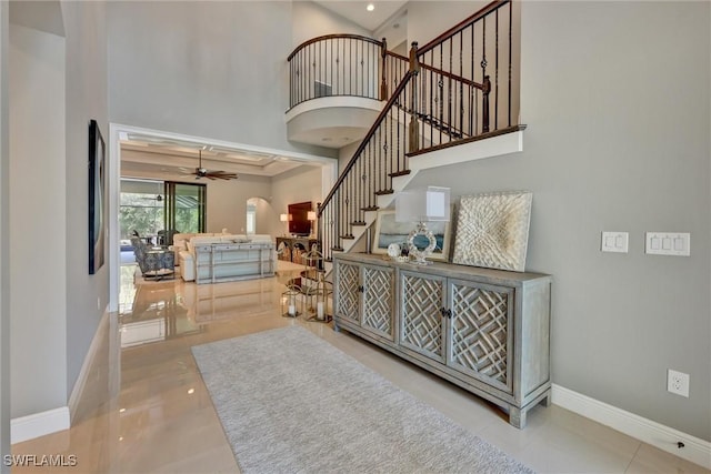 stairs featuring ceiling fan, a towering ceiling, and tile patterned flooring