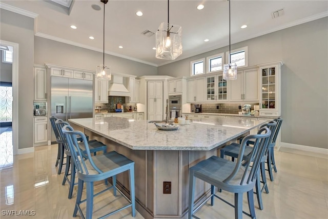 kitchen featuring premium range hood, appliances with stainless steel finishes, pendant lighting, and a large island