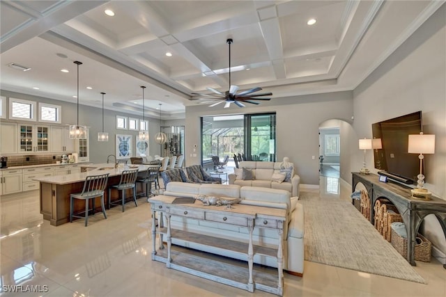 living room with ceiling fan, light tile patterned floors, beam ceiling, and coffered ceiling