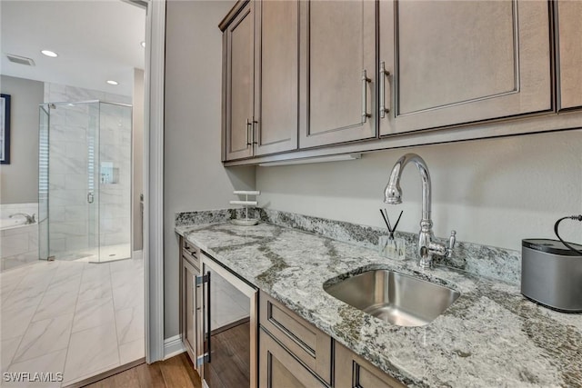 kitchen with light stone counters, sink, and beverage cooler