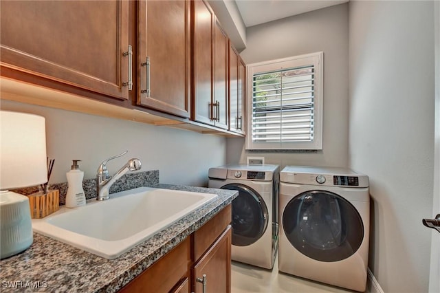 laundry room featuring sink, washing machine and clothes dryer, and cabinets