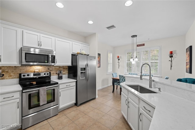 kitchen with pendant lighting, decorative backsplash, sink, stainless steel appliances, and white cabinets