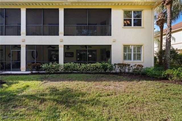 back of property featuring ceiling fan and a lawn