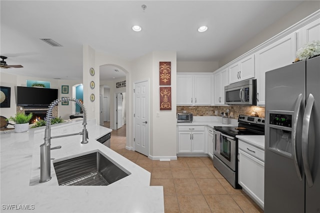 kitchen featuring backsplash, sink, light tile patterned floors, stainless steel appliances, and white cabinets