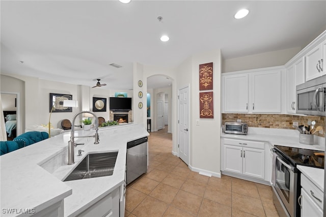 kitchen with stainless steel appliances, white cabinetry, tasteful backsplash, and sink