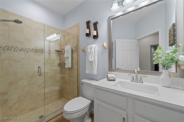 bathroom with a shower with shower door, vanity, and toilet