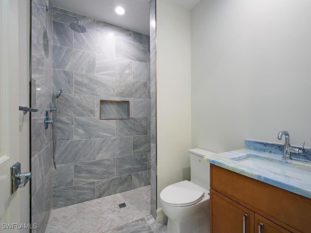 bathroom with toilet, vanity, and a tile shower