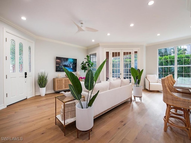 living room with light hardwood / wood-style floors, ceiling fan, crown molding, and french doors