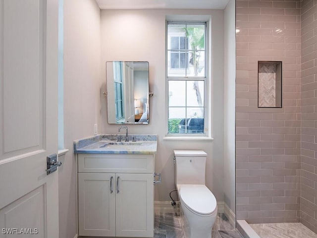 bathroom featuring plenty of natural light, toilet, vanity, and a tile shower