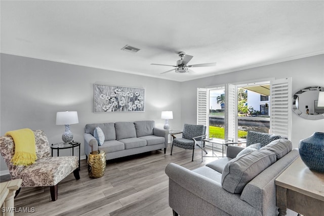 living room featuring ceiling fan, ornamental molding, and light hardwood / wood-style floors