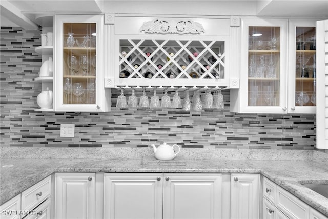 kitchen featuring backsplash, light stone counters, and white cabinets