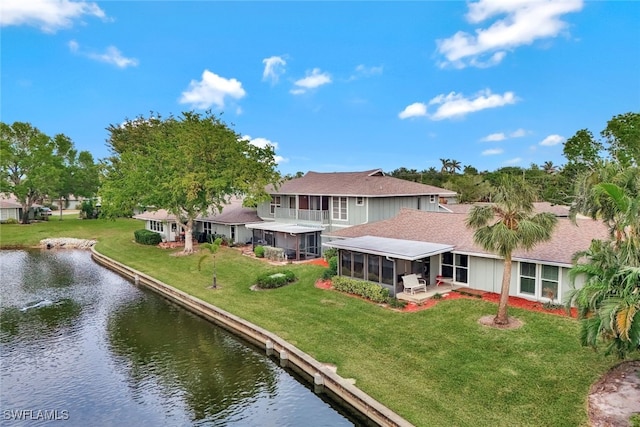 back of house featuring a balcony, a water view, a yard, and a sunroom