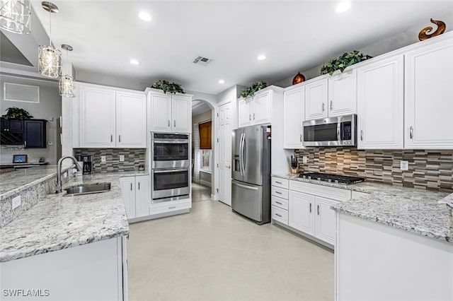 kitchen featuring white cabinetry, appliances with stainless steel finishes, decorative backsplash, pendant lighting, and sink