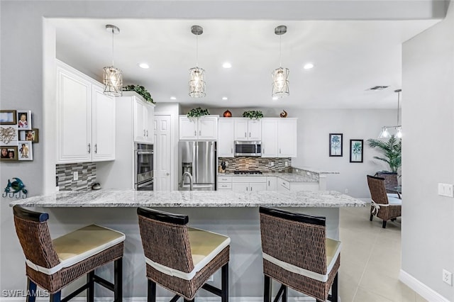 kitchen with a breakfast bar, kitchen peninsula, white cabinetry, hanging light fixtures, and appliances with stainless steel finishes