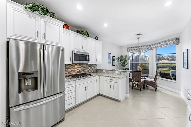 kitchen with white cabinetry, kitchen peninsula, appliances with stainless steel finishes, backsplash, and light stone countertops