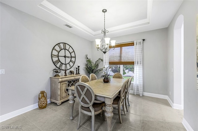 tiled dining space featuring a tray ceiling and a chandelier