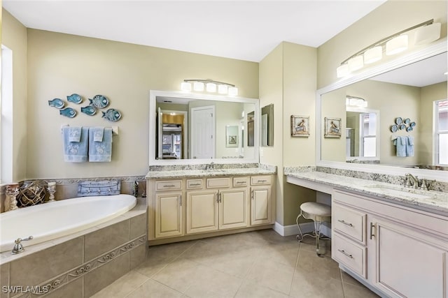 bathroom featuring a relaxing tiled tub, vanity, and tile patterned flooring