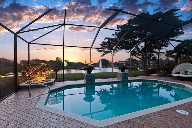 pool at dusk with a water view, a lanai, and a patio area