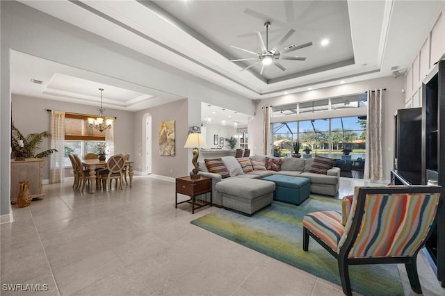 tiled living room featuring a raised ceiling and ceiling fan with notable chandelier