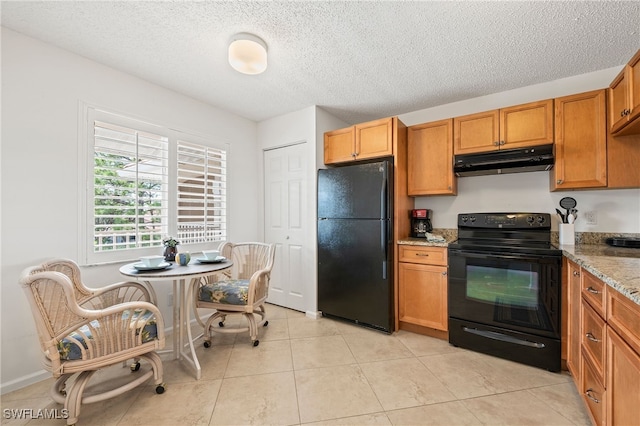 kitchen with light stone counters, light tile patterned floors, a textured ceiling, and black appliances