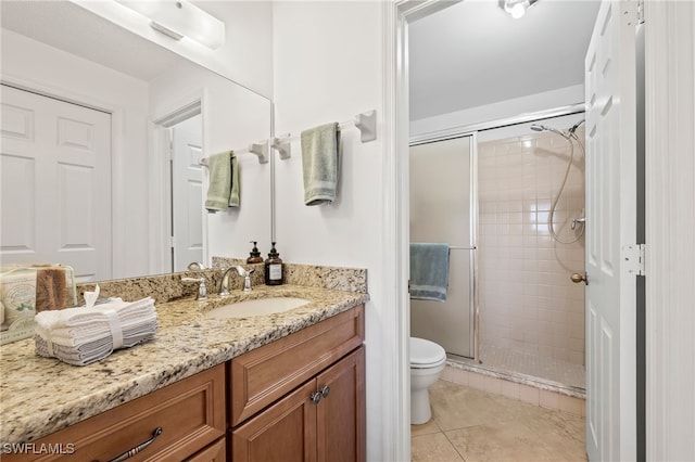 bathroom featuring toilet, vanity, tile patterned floors, and a shower with shower door