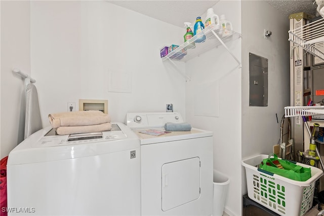 washroom featuring electric panel, washer and dryer, and a textured ceiling