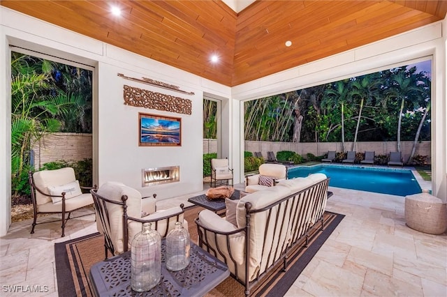 view of patio / terrace with a fenced in pool, a fenced backyard, and an outdoor living space with a fireplace