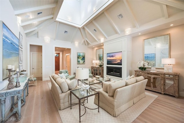 living room featuring light hardwood / wood-style floors, beam ceiling, and high vaulted ceiling