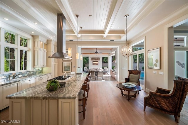 kitchen featuring decorative light fixtures, island range hood, cream cabinets, and a kitchen island