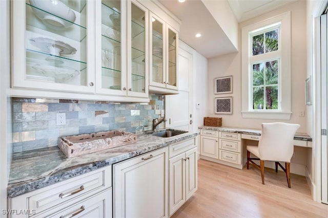 kitchen with sink, white cabinetry, light stone counters, and light hardwood / wood-style floors