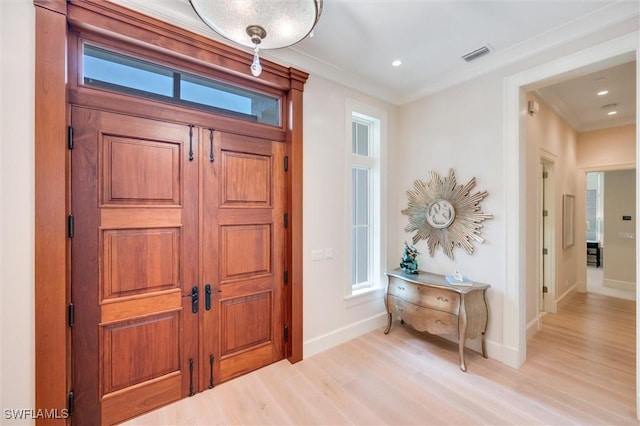 foyer entrance with light hardwood / wood-style flooring and ornamental molding