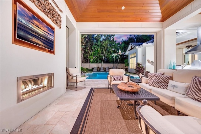 exterior space featuring ceiling fan, vaulted ceiling, wood ceiling, and a fireplace