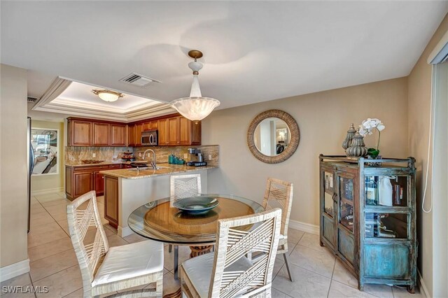 tiled dining room featuring a raised ceiling and sink