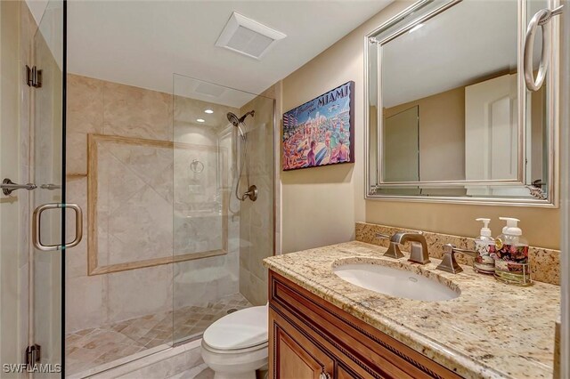 bathroom featuring vanity, toilet, and a shower with shower door