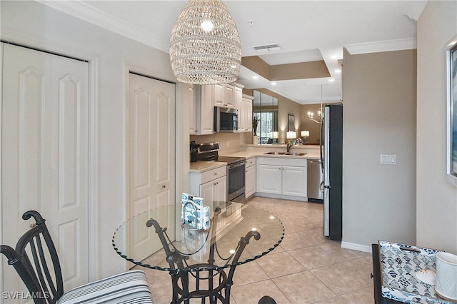 kitchen with white cabinetry, stainless steel appliances, decorative light fixtures, a chandelier, and sink