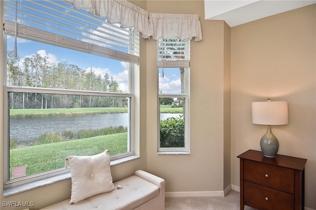 sitting room featuring a water view and carpet