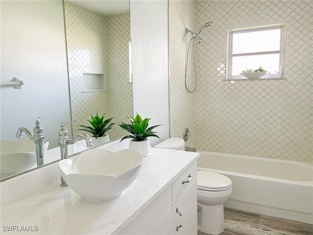 full bathroom with tiled shower / bath combo, vanity, hardwood / wood-style floors, and toilet