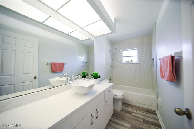 full bathroom featuring tiled shower / bath combo, vanity, hardwood / wood-style floors, and toilet